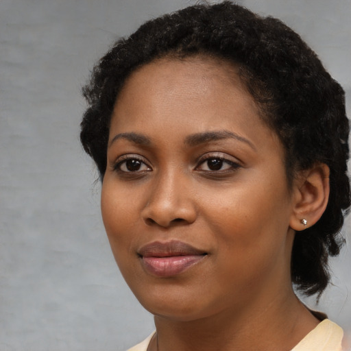 Joyful black young-adult female with short  black hair and brown eyes