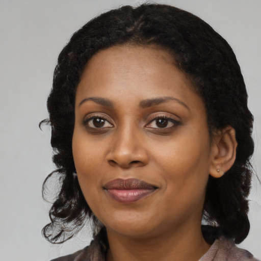 Joyful black young-adult female with long  black hair and brown eyes