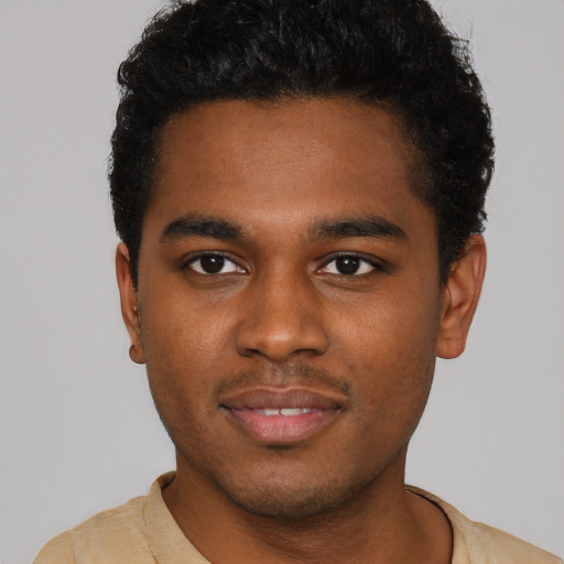 Joyful black young-adult male with short  brown hair and brown eyes