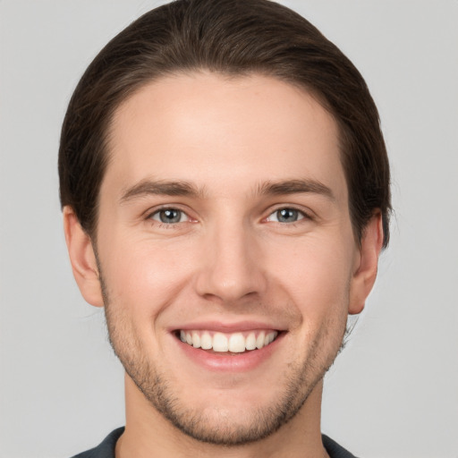 Joyful white young-adult male with short  brown hair and grey eyes