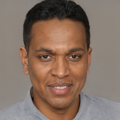 Joyful black adult male with short  black hair and brown eyes