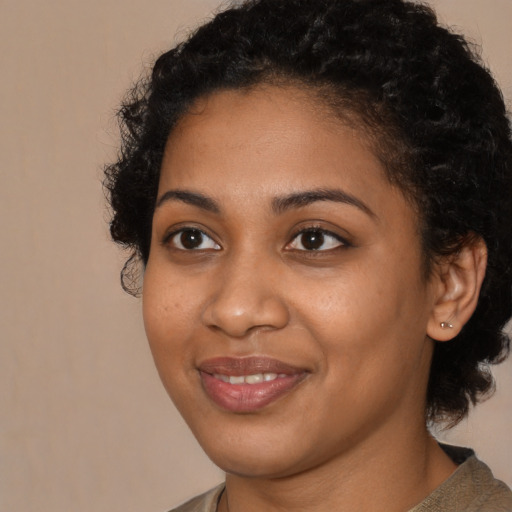 Joyful black young-adult female with long  brown hair and brown eyes