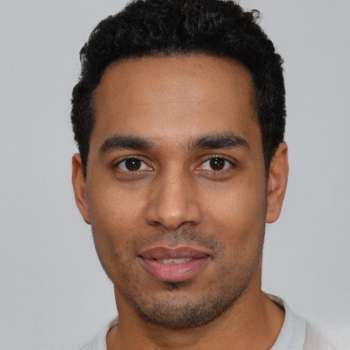 Joyful black young-adult male with short  black hair and brown eyes
