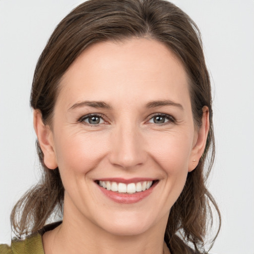 Joyful white young-adult female with medium  brown hair and grey eyes