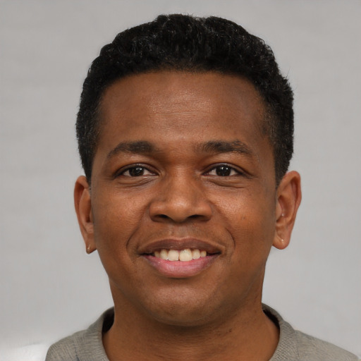 Joyful black young-adult male with short  brown hair and brown eyes