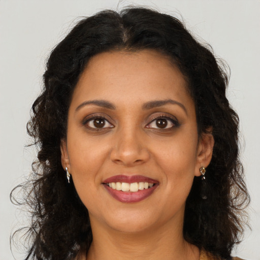 Joyful black young-adult female with long  brown hair and brown eyes