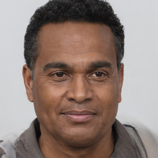 Joyful black adult male with short  black hair and brown eyes