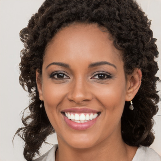 Joyful black young-adult female with long  brown hair and brown eyes