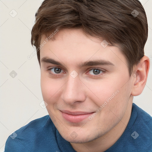 Joyful white young-adult male with short  brown hair and grey eyes