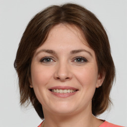 Joyful white young-adult female with medium  brown hair and grey eyes