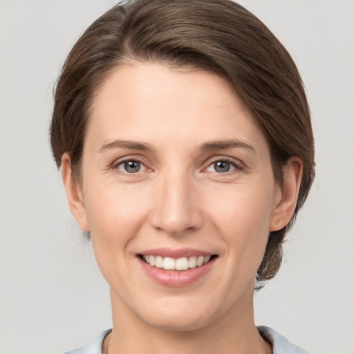 Joyful white young-adult female with medium  brown hair and grey eyes