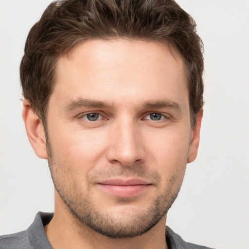 Joyful white young-adult male with short  brown hair and grey eyes