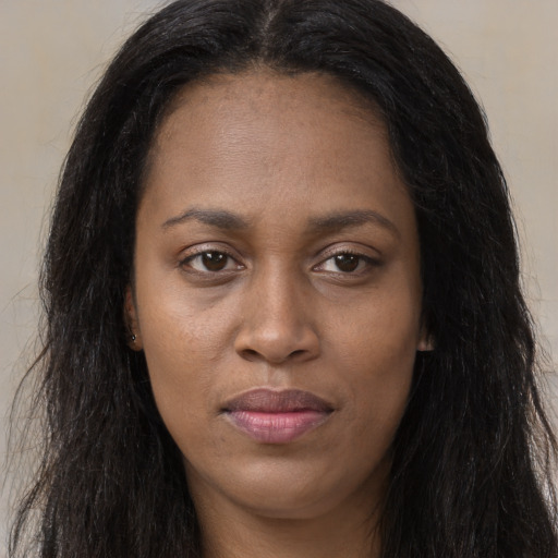 Joyful black young-adult female with long  brown hair and brown eyes