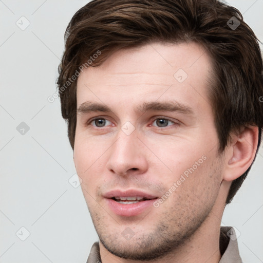 Joyful white young-adult male with short  brown hair and grey eyes