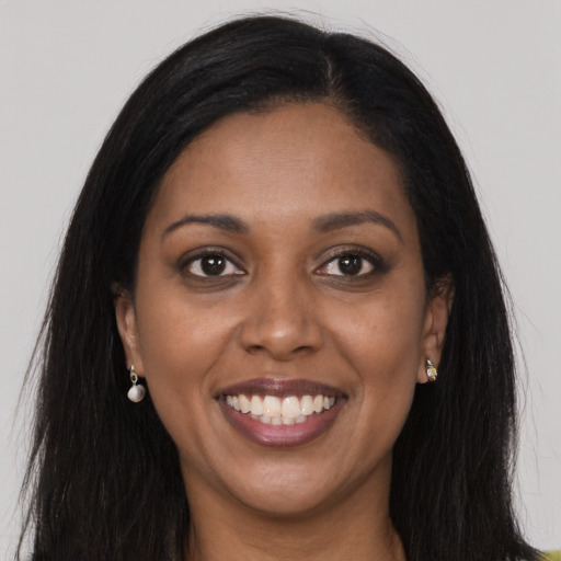 Joyful black young-adult female with long  brown hair and brown eyes