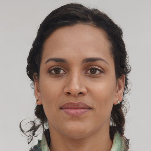 Joyful black young-adult female with long  brown hair and brown eyes
