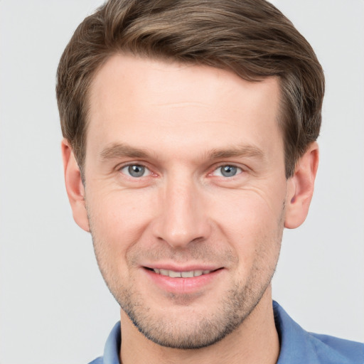 Joyful white young-adult male with short  brown hair and grey eyes