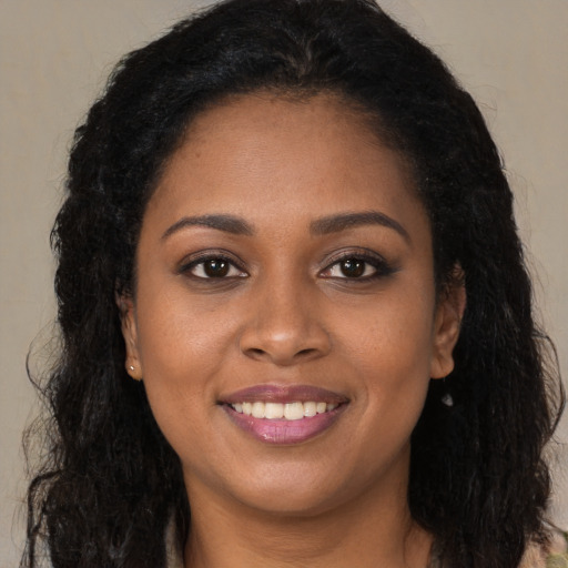 Joyful black young-adult female with long  brown hair and brown eyes