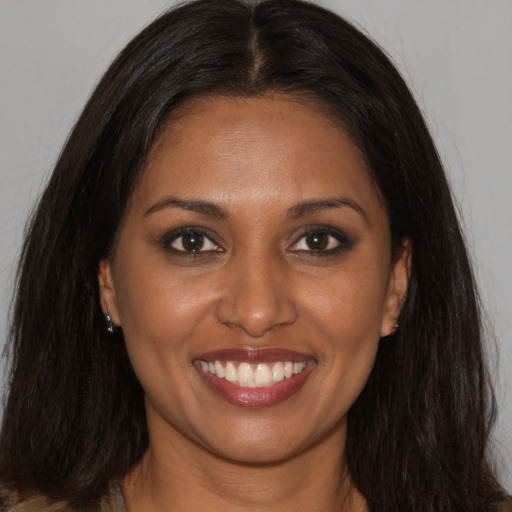 Joyful black young-adult female with long  brown hair and brown eyes