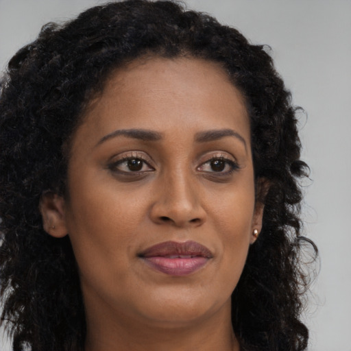 Joyful black young-adult female with long  brown hair and brown eyes