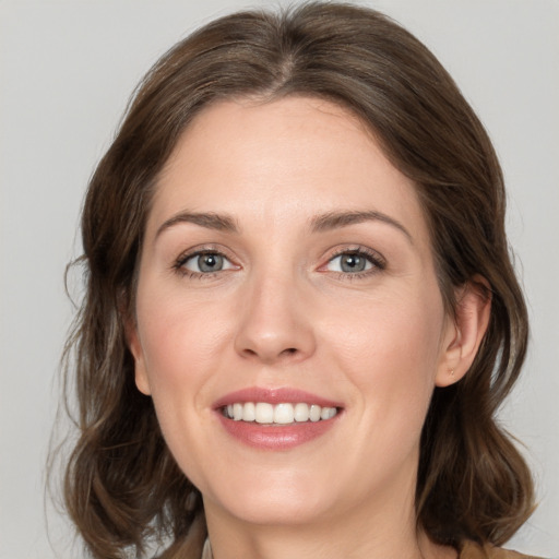 Joyful white young-adult female with medium  brown hair and grey eyes