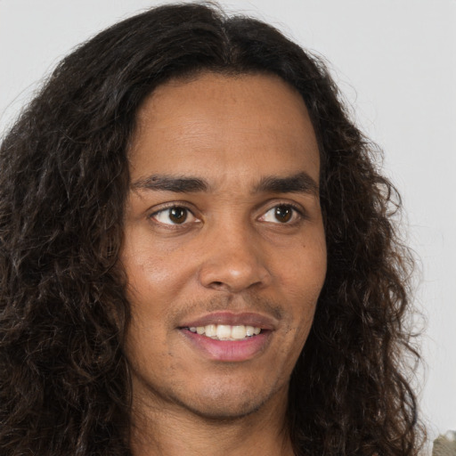 Joyful white young-adult male with long  brown hair and brown eyes