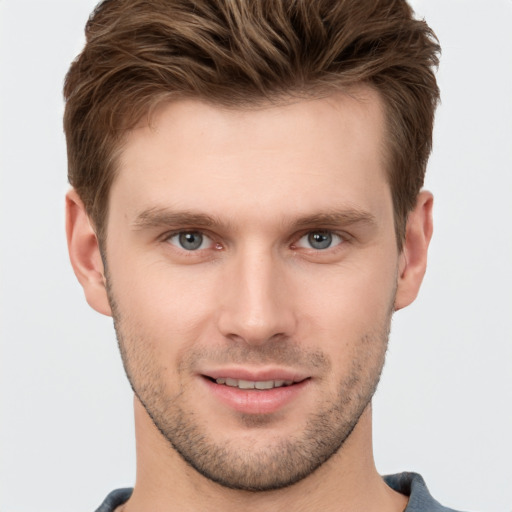 Joyful white young-adult male with short  brown hair and grey eyes