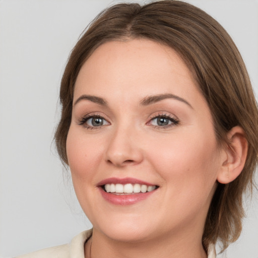 Joyful white young-adult female with medium  brown hair and grey eyes