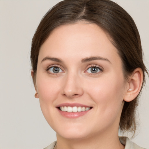 Joyful white young-adult female with medium  brown hair and grey eyes