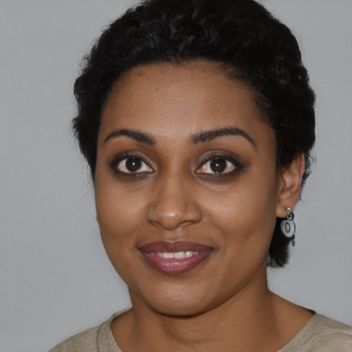 Joyful black young-adult female with short  black hair and brown eyes