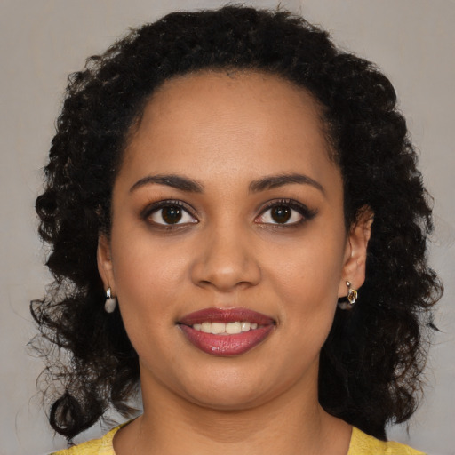Joyful black young-adult female with long  black hair and brown eyes