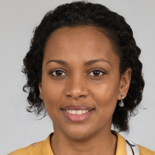 Joyful black young-adult female with long  brown hair and brown eyes