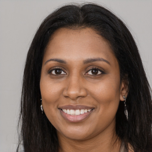 Joyful black young-adult female with long  brown hair and brown eyes