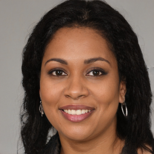 Joyful black young-adult female with long  brown hair and brown eyes