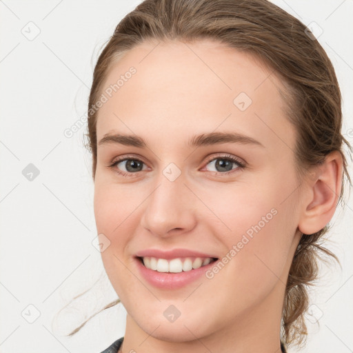 Joyful white young-adult female with medium  brown hair and grey eyes