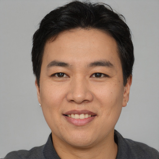 Joyful asian adult male with short  black hair and brown eyes