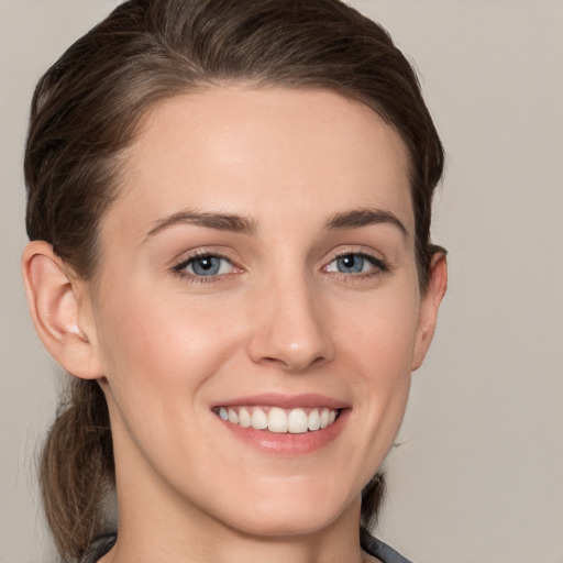 Joyful white young-adult female with medium  brown hair and grey eyes