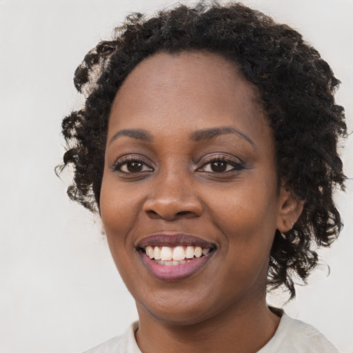 Joyful black young-adult female with long  black hair and brown eyes