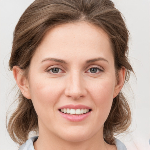 Joyful white young-adult female with medium  brown hair and grey eyes