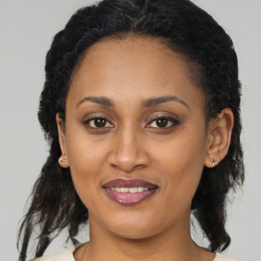 Joyful black adult female with long  brown hair and brown eyes