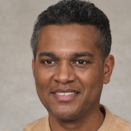 Joyful black young-adult male with short  black hair and brown eyes