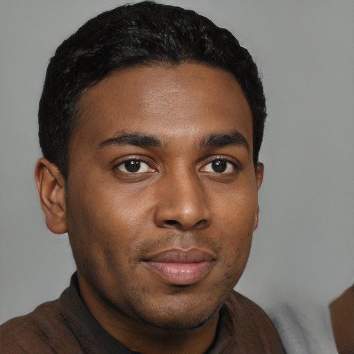 Joyful black young-adult male with short  black hair and brown eyes
