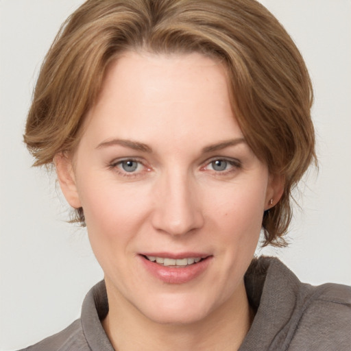 Joyful white young-adult female with medium  brown hair and grey eyes