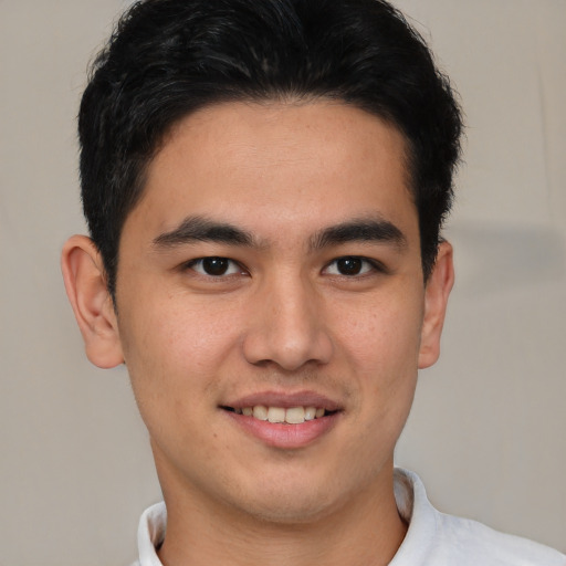 Joyful latino young-adult male with short  brown hair and brown eyes