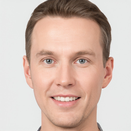 Joyful white young-adult male with short  brown hair and grey eyes