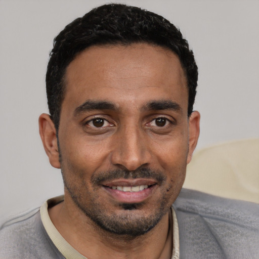 Joyful black young-adult male with short  black hair and brown eyes