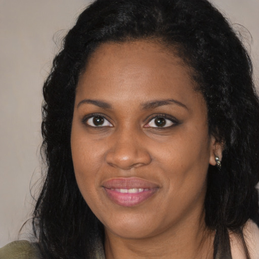 Joyful black young-adult female with long  brown hair and brown eyes