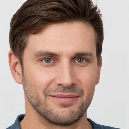 Joyful white young-adult male with short  brown hair and grey eyes