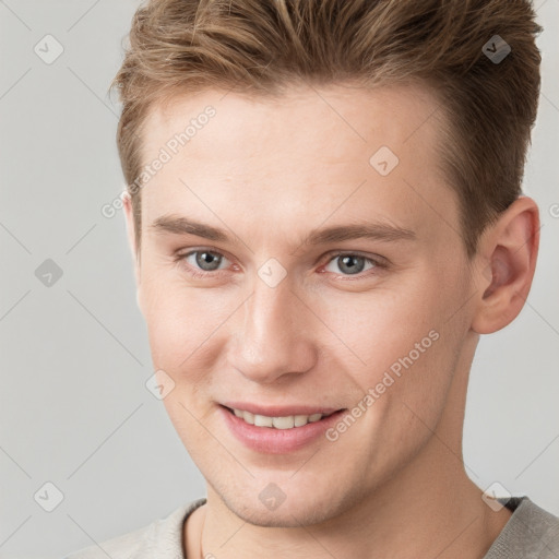 Joyful white young-adult male with short  brown hair and grey eyes