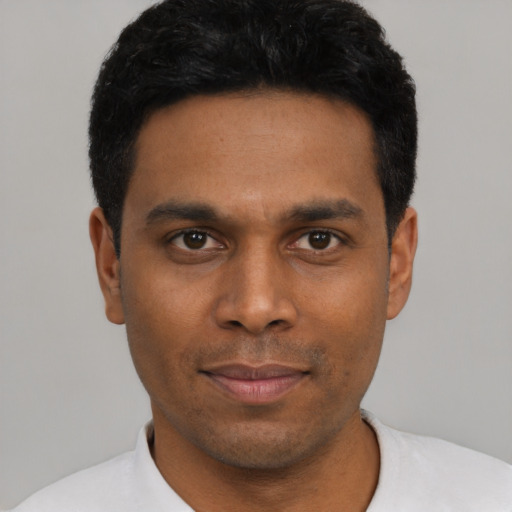 Joyful black young-adult male with short  black hair and brown eyes